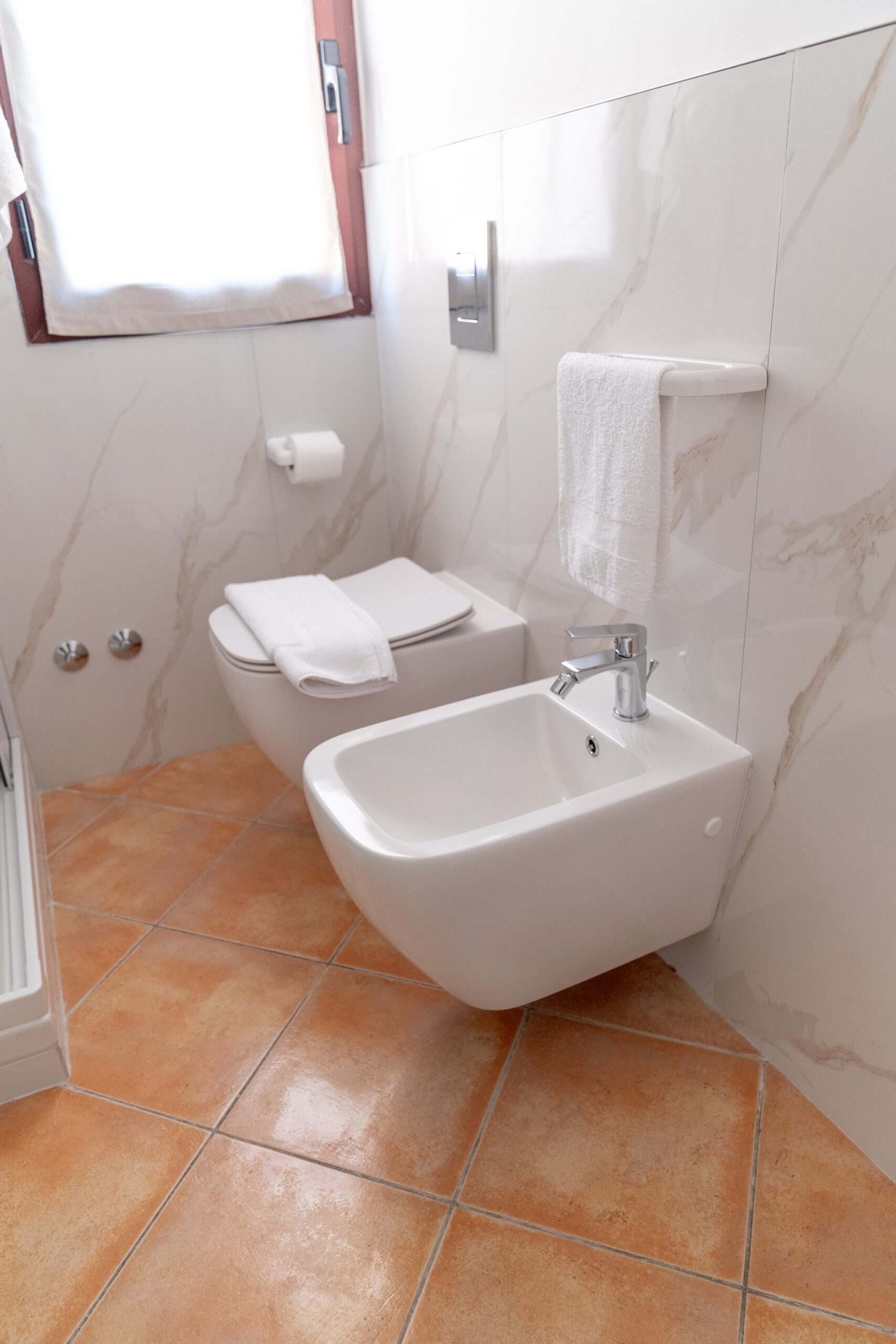 Bagno luminoso con sanitari bianchi e piastrelle arancioni al Residence La Cicala.