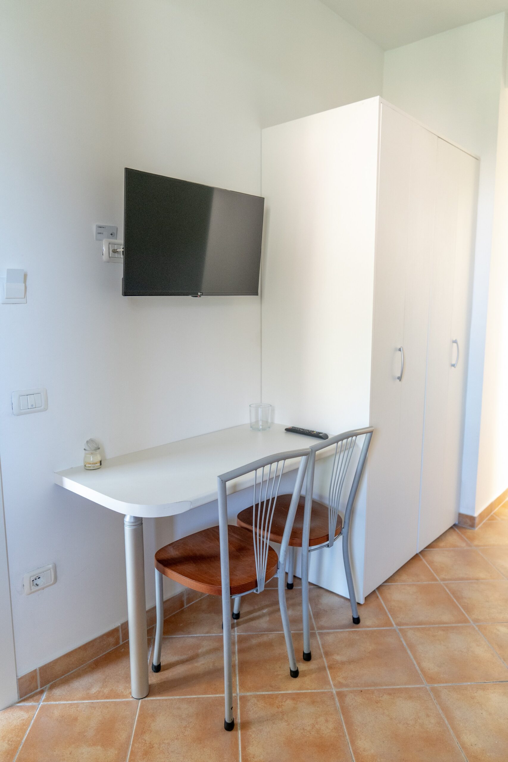 Interno camera Residence La Cicala con tavolo, sedie e TV.